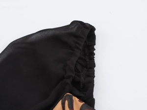 Détail d'une robe léopard avec d'élégantes manches en tulle noir et poignets plissés