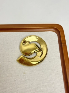 Detailed view of a gold swirl brooch on a beige fabric tray for French vintage styling