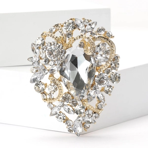 Close-up of a vintage heart-shaped gold brooch with large pear-cut crystal and rhinestones