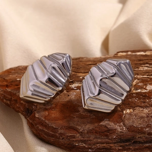 Détail macro de boucles d'oreilles géométriques argentées à surface métallique texturée