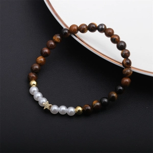 Détail d'un bracelet en perles d'œil de tigre et perles blanches avec breloque étoile dorée