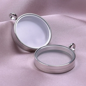 Close-up of circular stainless steel floating locket pendants on elegant pink silk