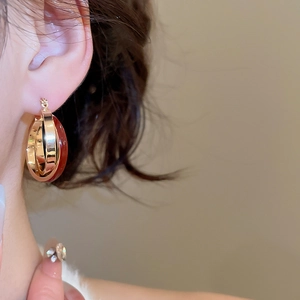 Close-up of vintage gold and burgundy enamel crossover hoop earrings on model