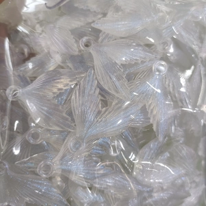 Close-up of luminous glitter fish tail charms in white acrylic, bulk DIY accessories