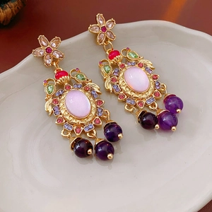 Detail view of vintage gold-tone floral earrings with pink gems and purple beads