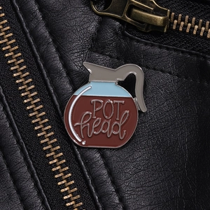 Macro view of a coffee pot enamel pin with POT head text on a black leather jacket