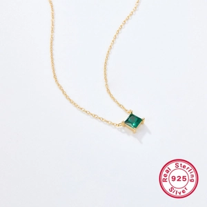 Detail of 925 sterling silver gold necklace with square green zircon pendant and four-prong setting