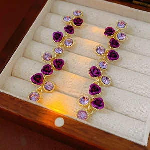 Détails des boucles d'oreilles dorées à pompons avec roses violettes et cristaux
