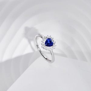 Macro shot of silver ring featuring heart-shaped blue stone and diamond halo