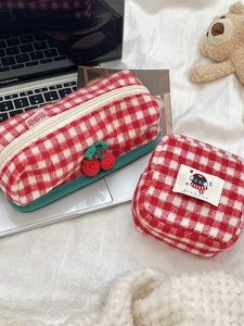 Red and white checkered knitted stationery pouch with cherry charm and cat patch on soft rug