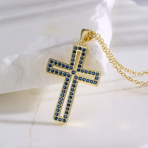 Gold plated hollow cross pendant necklace with blue zircon on white stone background