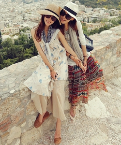 Outdoor street view of two women wearing foldable wide brim straw sun hats for summer vacation