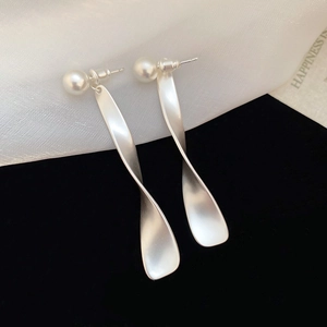Détail des boucles d'oreilles torsadées en argent S925 avec perles blanches élégantes