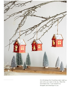 Close-up of LED wooden Christmas house ornaments with warm glow hanging on branches