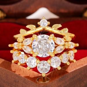 Macro view of gold three-piece ring set with crystals on red velvet jewelry box cushion