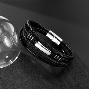 Macro detail of multi-layer black braided leather bracelet with silver magnetic steel clasp