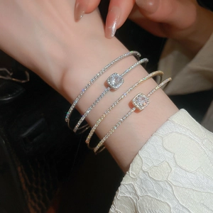 Close-up of stacked gold and silver bangles with square-cut zircon on a model's wrist