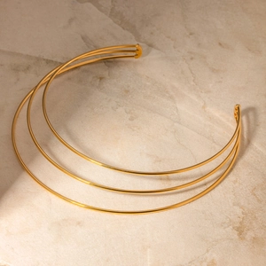 Detailed view of triple-layered 14K gold stainless steel choker on beige marble