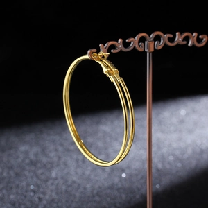 Close-up of large gold-tone hoop earrings hanging on a vintage decorative metal stand