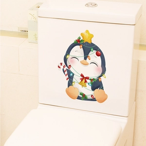 Detail of a Christmas penguin sticker with festive lights on a white toilet tank surface