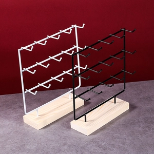 Close-up of metal jewelry display rack with multiple hooks and solid wooden base