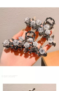 Handheld detail of large shark hair clip with white camellia and black rhinestones