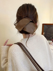 Detailed close-up of dark brown leather texture bow hair clip on model back view