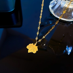 Close-up of golden maple leaf pendant with fine vein texture on polished chain