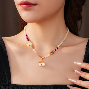 Close-up of vintage enamel flower basket pendant with zircon on a gold chain worn by model