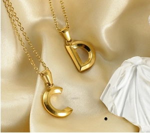 Detail of 18K gold-plated stainless steel letter pendants with natural shell inlay