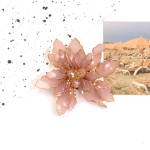 Elegant pink acrylic flower brooch with golden edges and beads on a stylish background