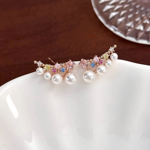 Macro shot of rose gold flower earrings with colorful zircons and delicate pearls