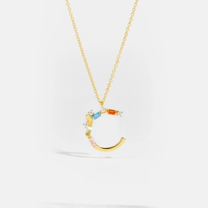 Macro detail of gold letter C pendant with colorful zircon stones on a fine chain