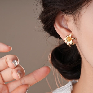 Elegant gold flower stud earrings featuring layered petals shown on ear for fashion style