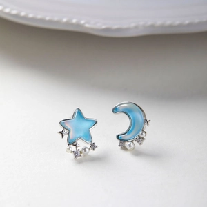 Macro shot of asymmetric blue star and moon earrings with pearls and crystals