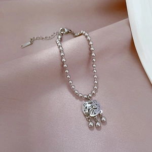 Detail of silver beaded bracelet featuring a Chinese Fu character lock and small bells