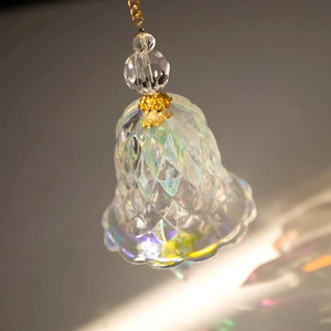 Macro shot of bell-shaped rainbow crystal suncatcher with diamond texture and gold chain