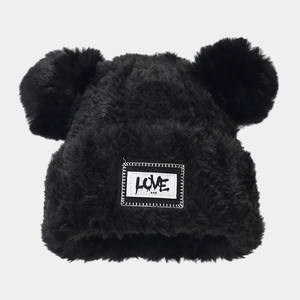 Détail du bonnet d'hiver noir avec deux pompons en fausse fourrure et patch lettre d'amour