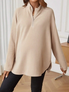 Detail of beige fleece maternity pullover featuring half-zip collar and side slit hem
