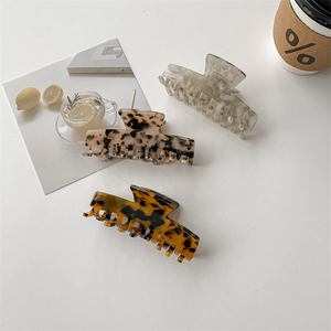 Three acetate hair claws in leopard and marble patterns displayed on white surface