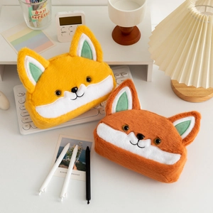 Close-up of cute plush fox pencil cases in yellow and orange on a desk with keyboard
