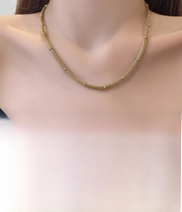 Detail of vacuum plated titanium steel gold chain with delicate metallic beads