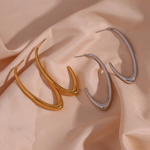 Detailed view of minimalist V-shaped gold and silver earrings on champagne satin cloth