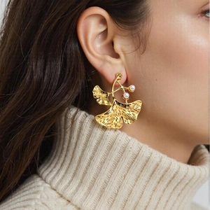 Elegant gold ginkgo leaf earrings with pearls shown on model in a soft-lit close-up shot