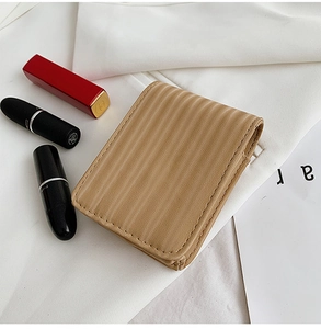 Detail of tan mini lipstick pouch with wavy texture, mirror, and portable travel design