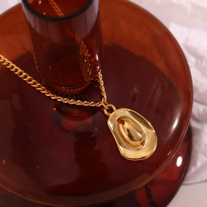 Macro detail of a vintage 18K gold plated hat pendant on a polished stainless steel chain
