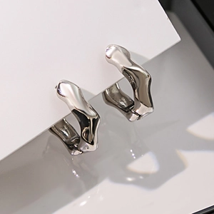 Détail de boucles d'oreilles créoles argentées avec motif ondulé irrégulier