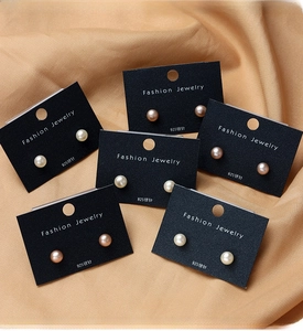Detailed close-up of natural freshwater pearl earrings in various colors on display card