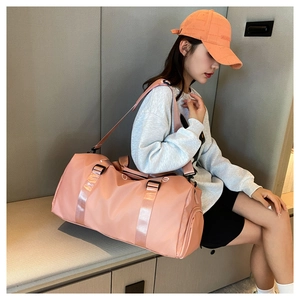 Model wearing a pink waterproof fitness travel bag with adjustable strap and dual handles