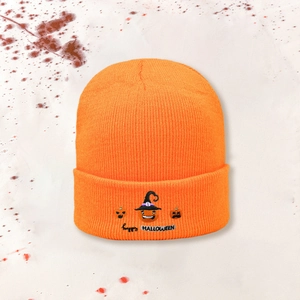 Orange knitted Happy Halloween beanie with embroidered pumpkin on a themed background